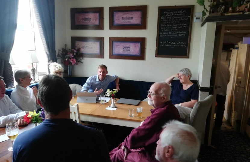 Lee Rowley at a table talking with residents